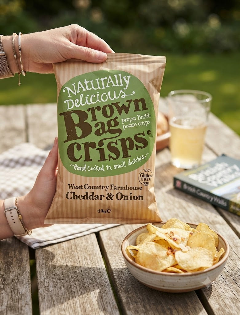 Brown Bag Crisps West Country Farmhouse Cheddar & Onion snack pack, 40g, showing crispy chips in a colorful bag.