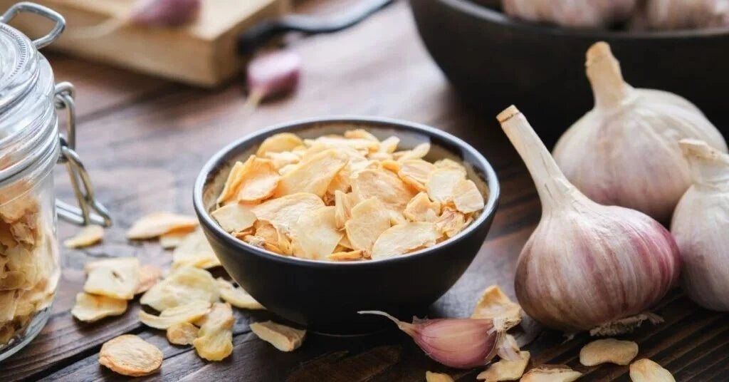 Reign Goods premium dehydrated garlic flakes in a clear jar, aromatic dried garlic for cooking and seasoning in bulk.
