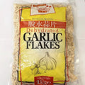 Reign Goods premium dehydrated garlic flakes in a clear jar, aromatic dried garlic for cooking and seasoning in bulk pantry.